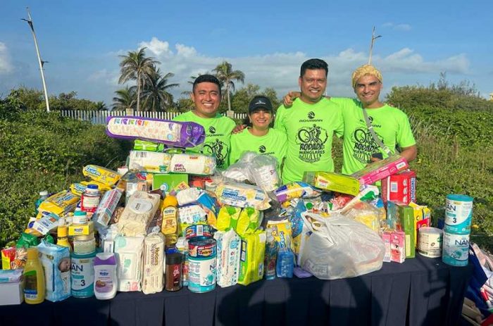 Participantes de la Rodada por los Manglares en Isla Mujeres entregando donaciones a miembros de la Fundación Desde Cero